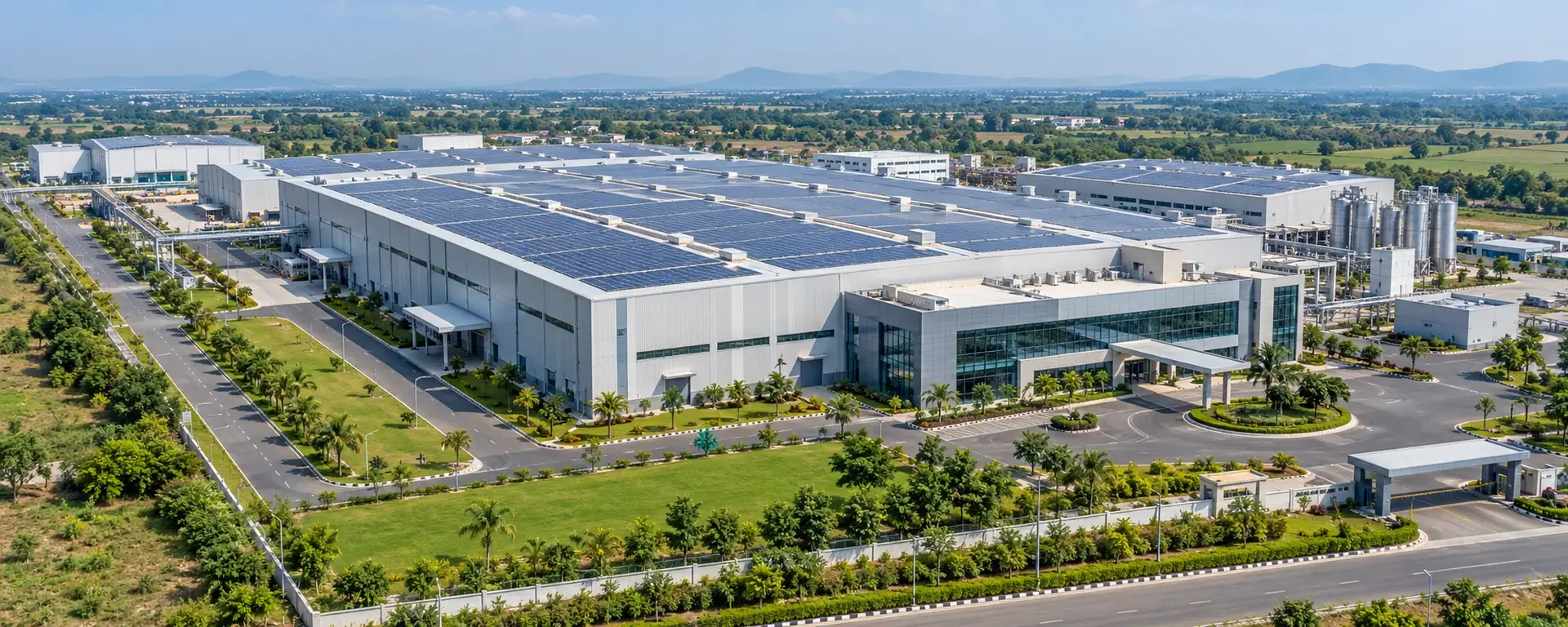 Aerial view of a clean modern industrial plant with a solar roof, access roads and landscaped grounds